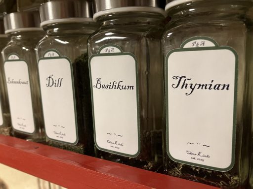 Gewürzgläser mit individuellen Etiketten im Retro-Design stehen auf einem Regal.